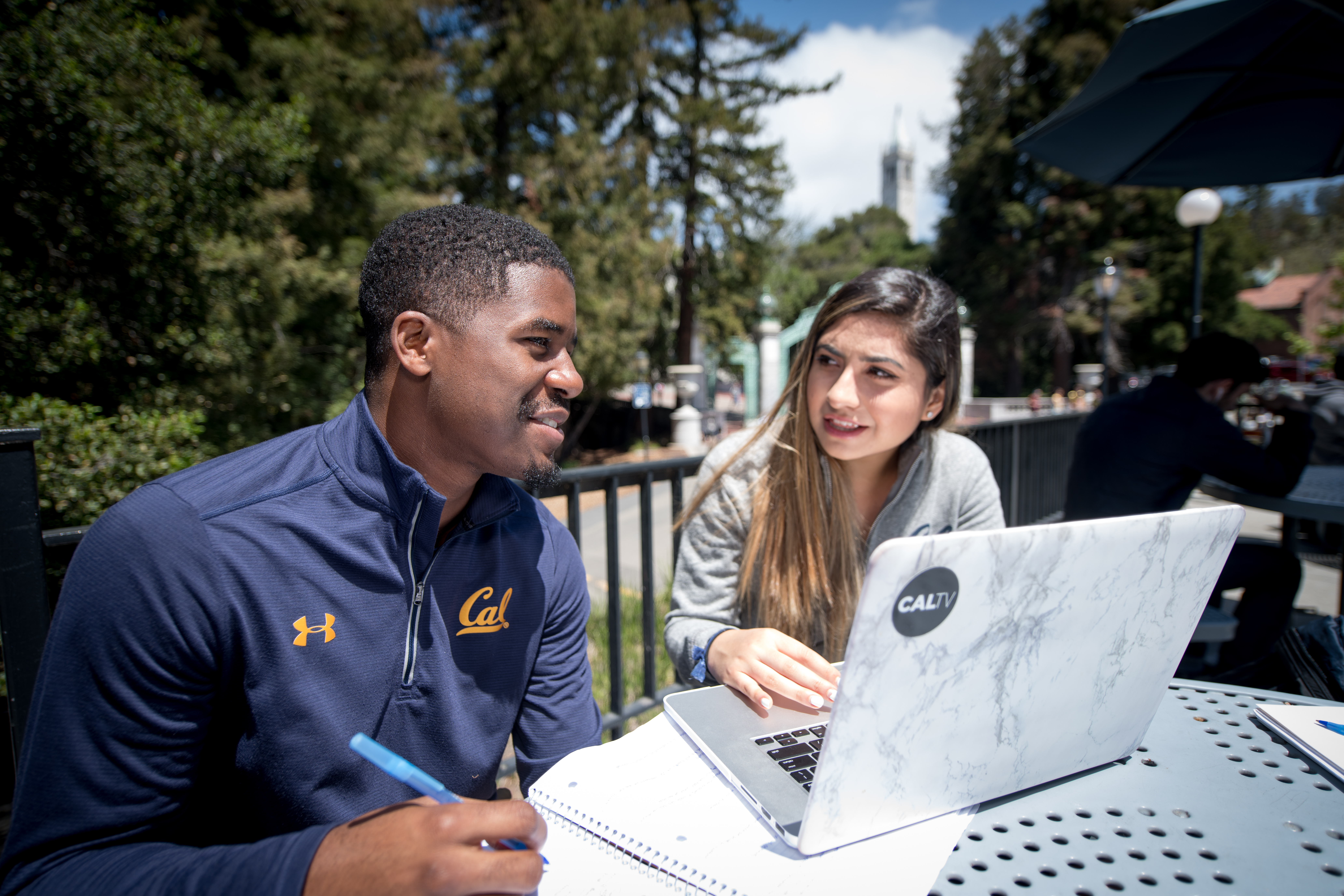 Two Berkeley students studying together outside with laptop.