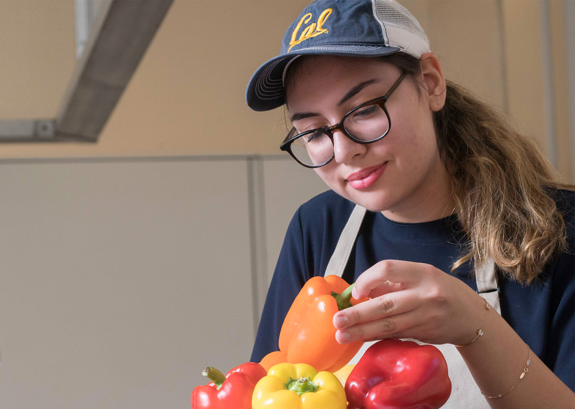 A young person holding red and orange peppers