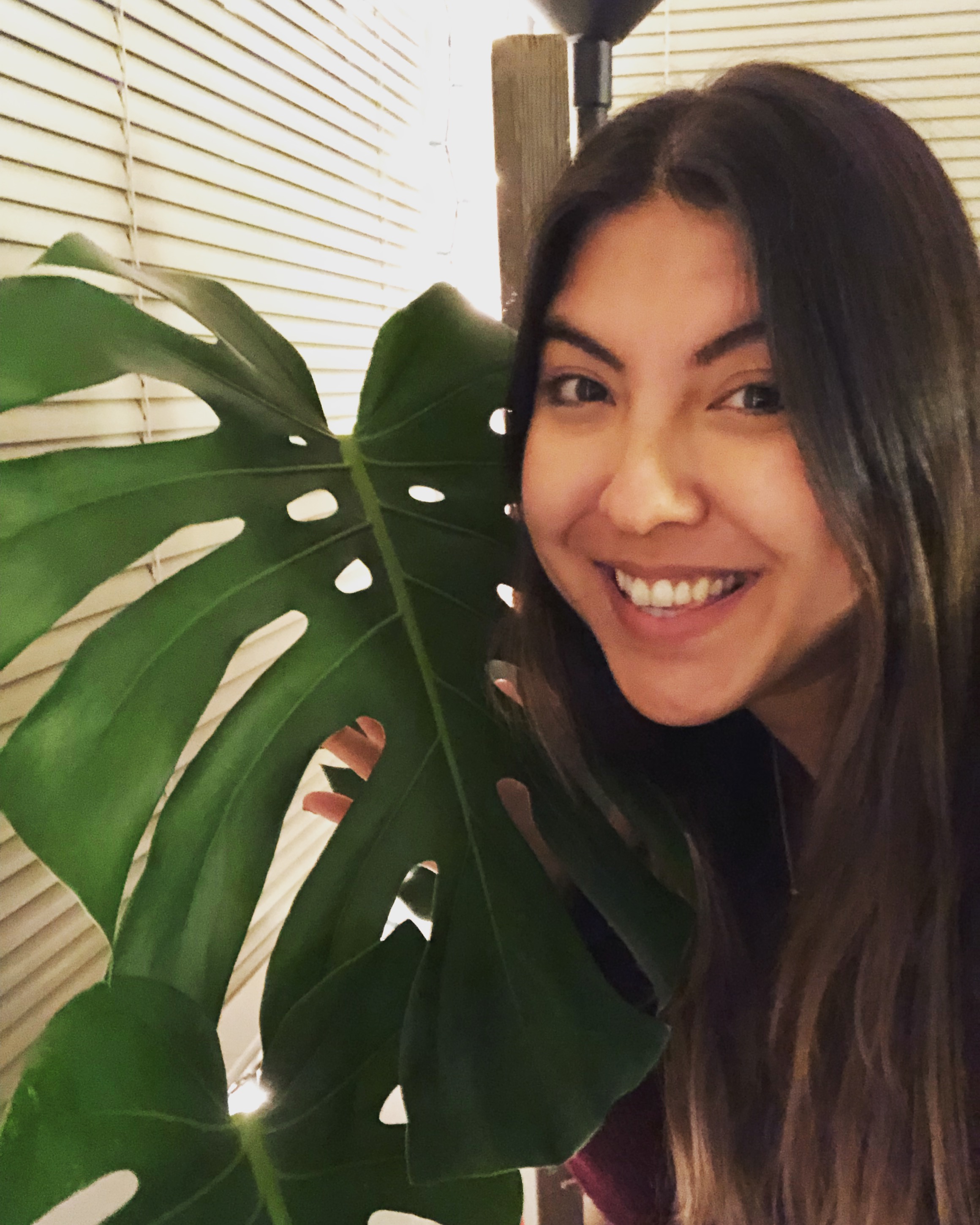 Yasasha smiling next to a large leaf.