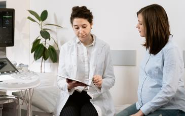 A doctor and pregnant person looking at a chart